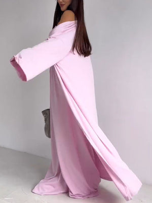 Blush pink off-the-shoulder maxi dress with long sleeves and high slits, styled with a grey bag.