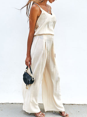 Cream cami and pleated palazzo pants set with a subtle sheen, styled with a black handbag.