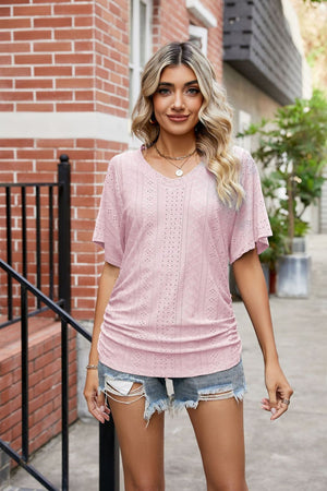 Pink perforated dolman sleeve blouse with V-neck and side ruching.