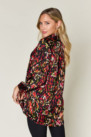 Silk tie-neck blouse with abstract print in black, red, and green.