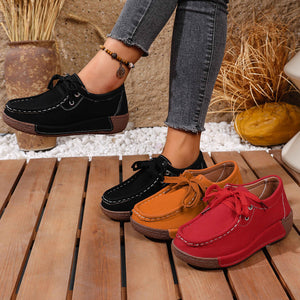 Lace-up moccasin style flats in black, orange, and red with white stitching detail.
