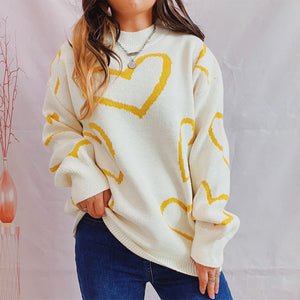White knit sweater with yellow heart pattern, crew neck, long sleeves.