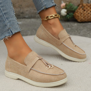 Khaki flat slip-ons with decorative strap detail and contrast piping.