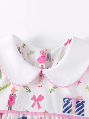 Toddler dress with Peter Pan collar, white cotton with pink trim, featuring a whimsical print of figures and gifts.