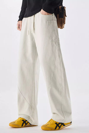 Men's relaxed fit off-white cotton jeans with drawstring waist and utility pockets.