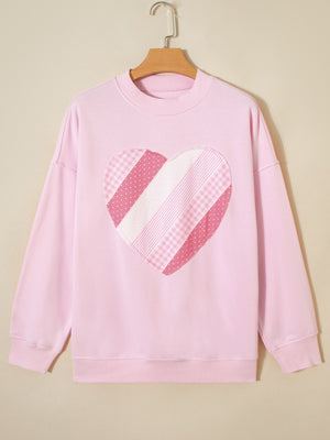 Pink cotton crew neck sweatshirt with a patchwork heart graphic.