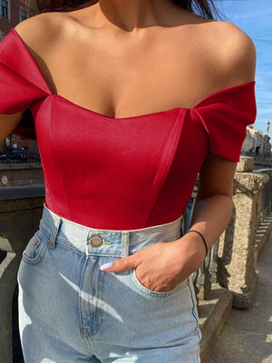 Red sweetheart neckline off-shoulder blouse with bow sleeves, styled with light wash jeans.