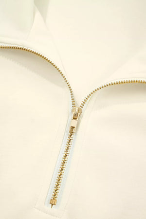 Cream cotton zip blouse with stand-up collar and ruffled detail.