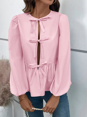 Blush pink peplum blouse with keyhole neckline and bow details, long puffed sleeves.