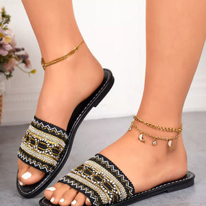 Black embroidered artisan open-toe sandals with bohemian detail and gold anklets.
