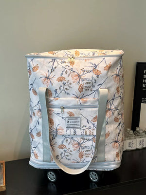 Charming floral rolling travel bag in white with a blue and orange floral pattern, featuring dual handles and wheels.