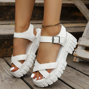 White platform ankle strap sandals with criss-cross straps and chunky sole.