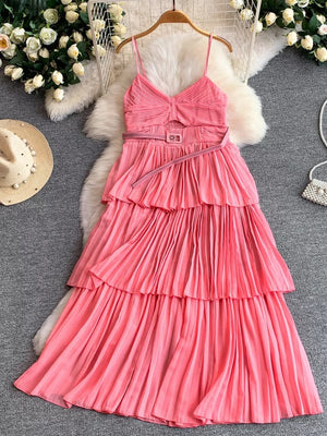 Pink pleated midi dress with spaghetti straps, V-neck, cut-out waist, and tiered skirt.