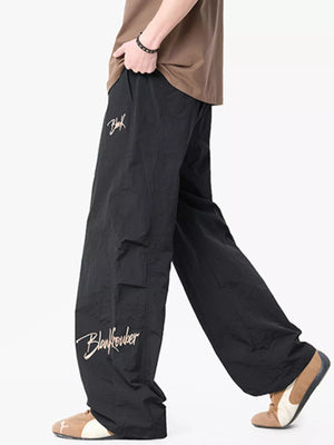 Black wide-leg drawstring pants with embroidered logo detail and cargo pockets.
