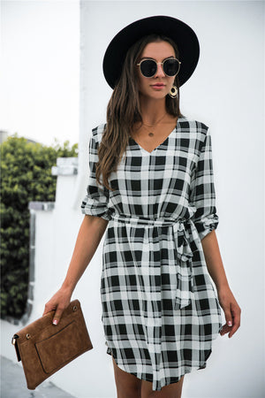 Black plaid shirtdress with V-neck, 3/4 sleeves, and belted waist.