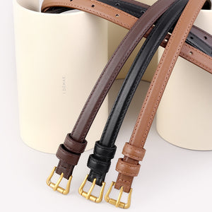 Elegant cowhide leather belts in black, caramel, and brown with gold buckles.