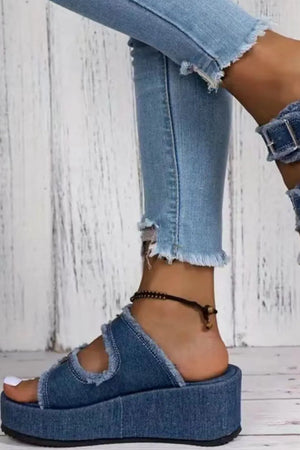 Denim platform slides with buckle detail and frayed edges.