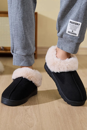 Black suede house slippers with plush shearling trim.