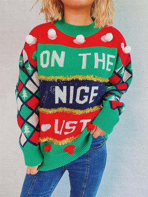 Green crewneck sweater with "On The Nice List" graphic, pom-pom details, and argyle sleeves.