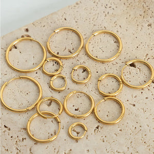 Gold vermeil huggie earrings in various sizes, displayed on a textured surface.