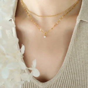 Delicate duo pendant necklace in gold with a single clear stone accent.