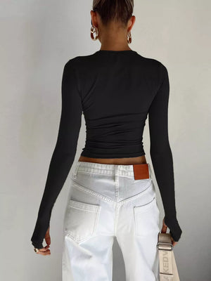 Black long sleeve t-shirt with ruching detail and thumbholes, worn with white jeans.
