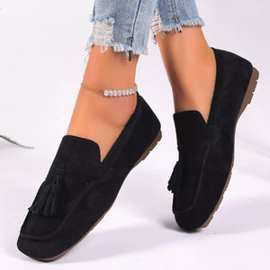 Black suede slip-on loafers with tassel detail and ankle bracelet