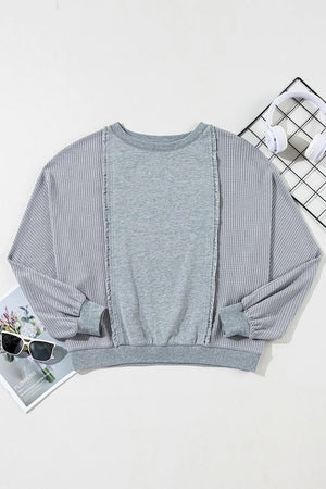 Gray waffle knit top with fringe trim and crew neck.