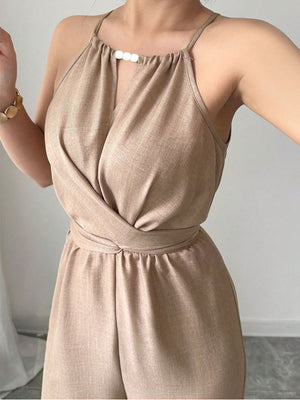 Halter neck wide leg jumpsuit in beige with a tie waist and decorative beads at the neckline.
