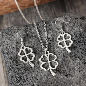 Silver four-leaf clover pendant necklace and matching dangle earrings jewelry set.