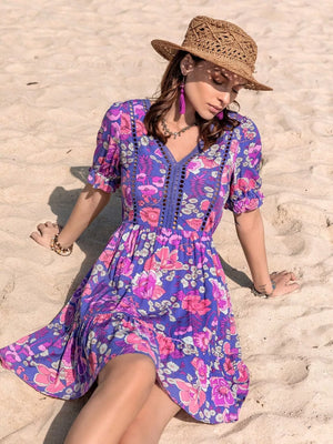Vibrant floral eyelet mini dress with V-neck, short puff sleeves, and tiered skirt.