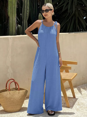 Blue tie-strap wide-leg romper with textured fabric and adjustable shoulder ties.