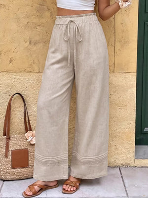 Beige wide-leg maternity trousers with drawstring waist and lace trim detail.
