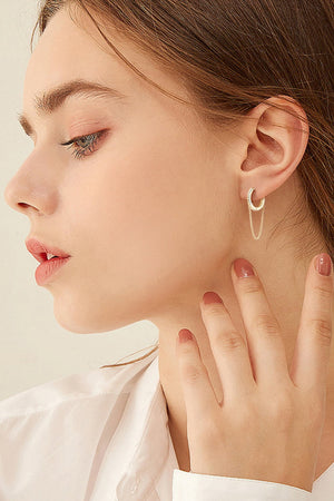 Gold dangling chain pavé huggie earrings with delicate chain detail.