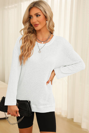 White waffle knit oversized top with crew neck and long sleeves, slit hem detail.