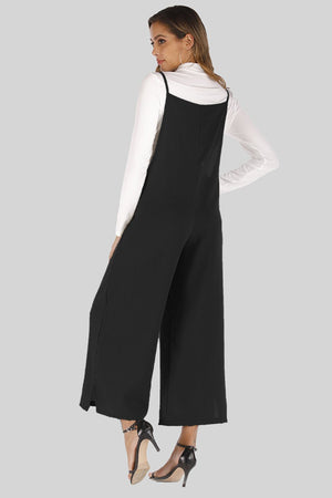 Black culotte overalls with slender straps and wide legs, styled over a white long-sleeve top.