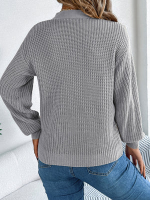 Gray cable knit sweater with cutout detail and balloon sleeves.