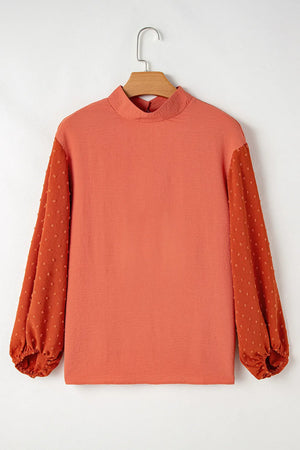 Orange blouson top with mock neck and textured Swiss dot puff sleeves