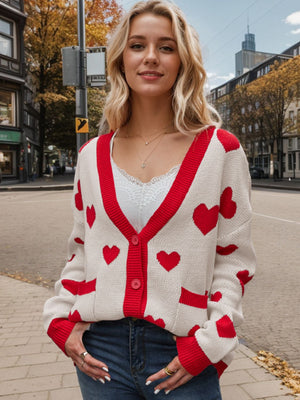 Cream knit cardigan with red hearts, red trim, and buttons.