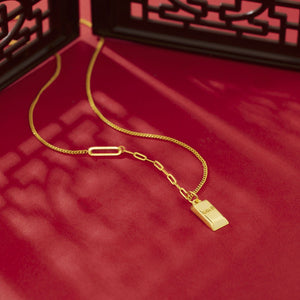 Gold-plated bar pendant necklace with curb links and paperclip chain detail.