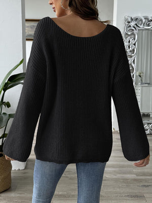 Black slouchy boatneck knit sweater with wide sleeves and ribbed texture.
