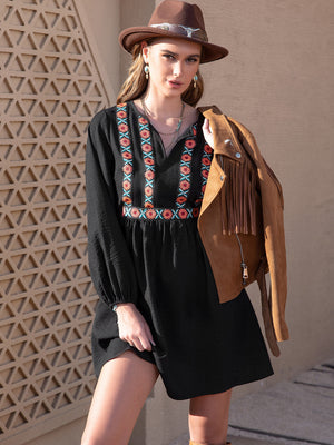 Black mini dress with embroidered yoke and V-neck, long sleeves, A-line cut.