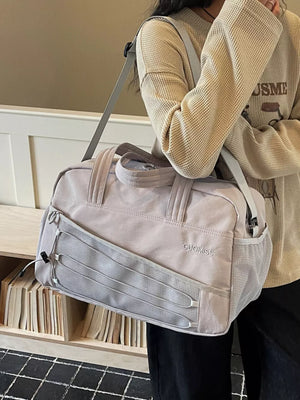 Grey nylon travel bag with mesh side pockets and bungee cord detail.