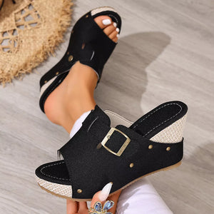 Black wedge sandals with decorative gold buckle and stud accents.