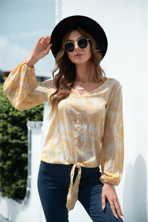 Tie-front blouson top in light yellow with a swirl print and balloon sleeves.