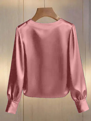 Pink satin blouse with round neck, long sleeves, and pearl trim detail.