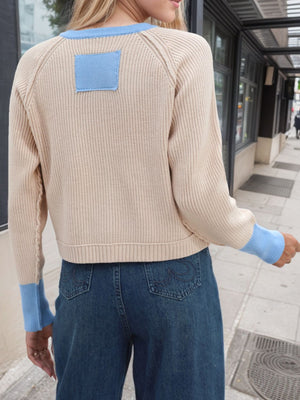 Raglan sleeve knit cardigan in tan with blue trim and patch detail.