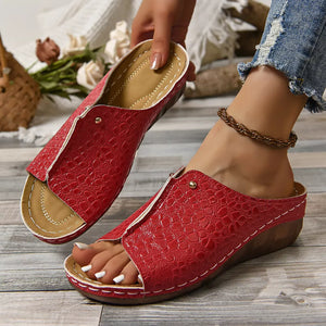Red glossy crocodile-embossed wedge sandals with open toe and white stitching detail.