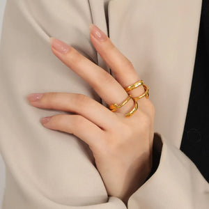 Gold sculptural spiral steel ring with open ends on a woman's hand.
