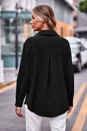 Black oversized utility shirt with pleated back detail and button cuffs.